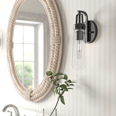 black bathroom sconce next to a white rope mirror